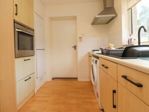 A compact kitchen with a built-in oven, a washing machine, and a sink. - Wynnville (Skipton)
