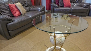 Un salon avec deux canapés en cuir, une table basse en verre et un rideau rouge.