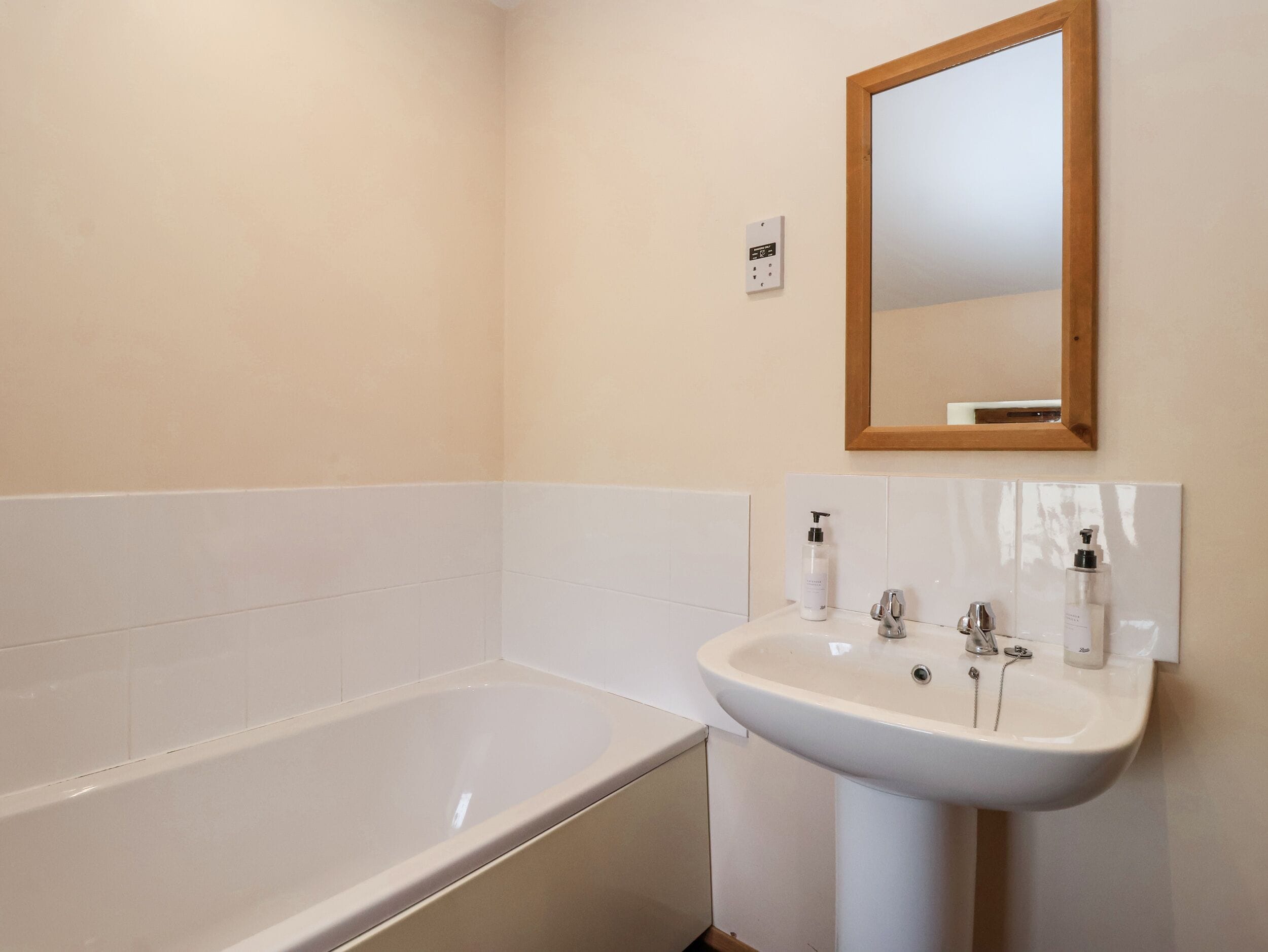 A bathroom with a bathtub, a sink, and a mirror.