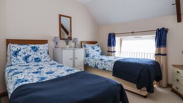 A bedroom with two beds, a dresser, a mirror, and a window with curtains.