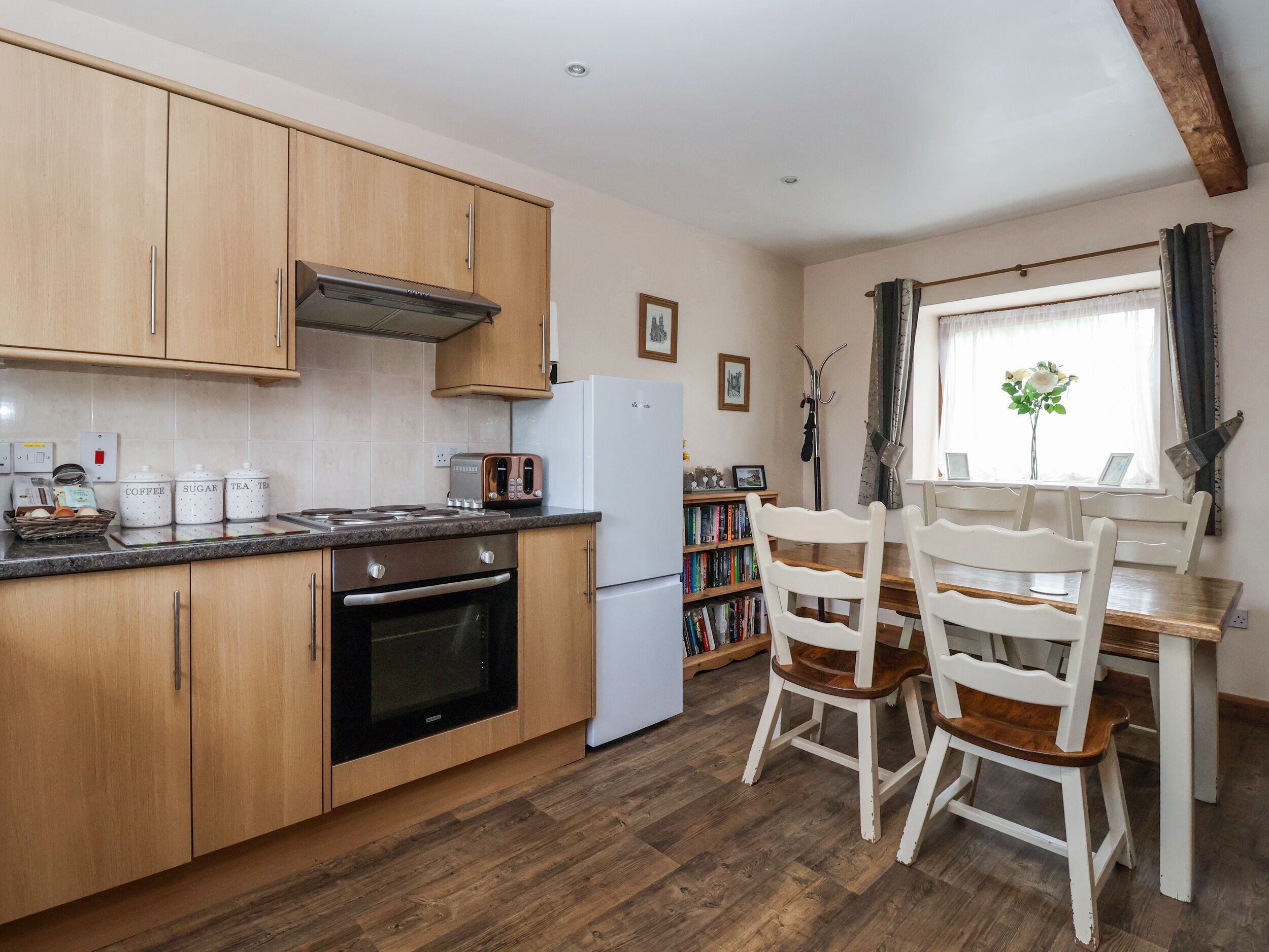 A kitchen with wooden cabinets, a stove, a refrigerator, and a dining table with chairs.