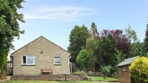 A single-story stone house with a pitched roof, a small front porch, and a well-maintained lawn. - Matlock Green (Matlock)