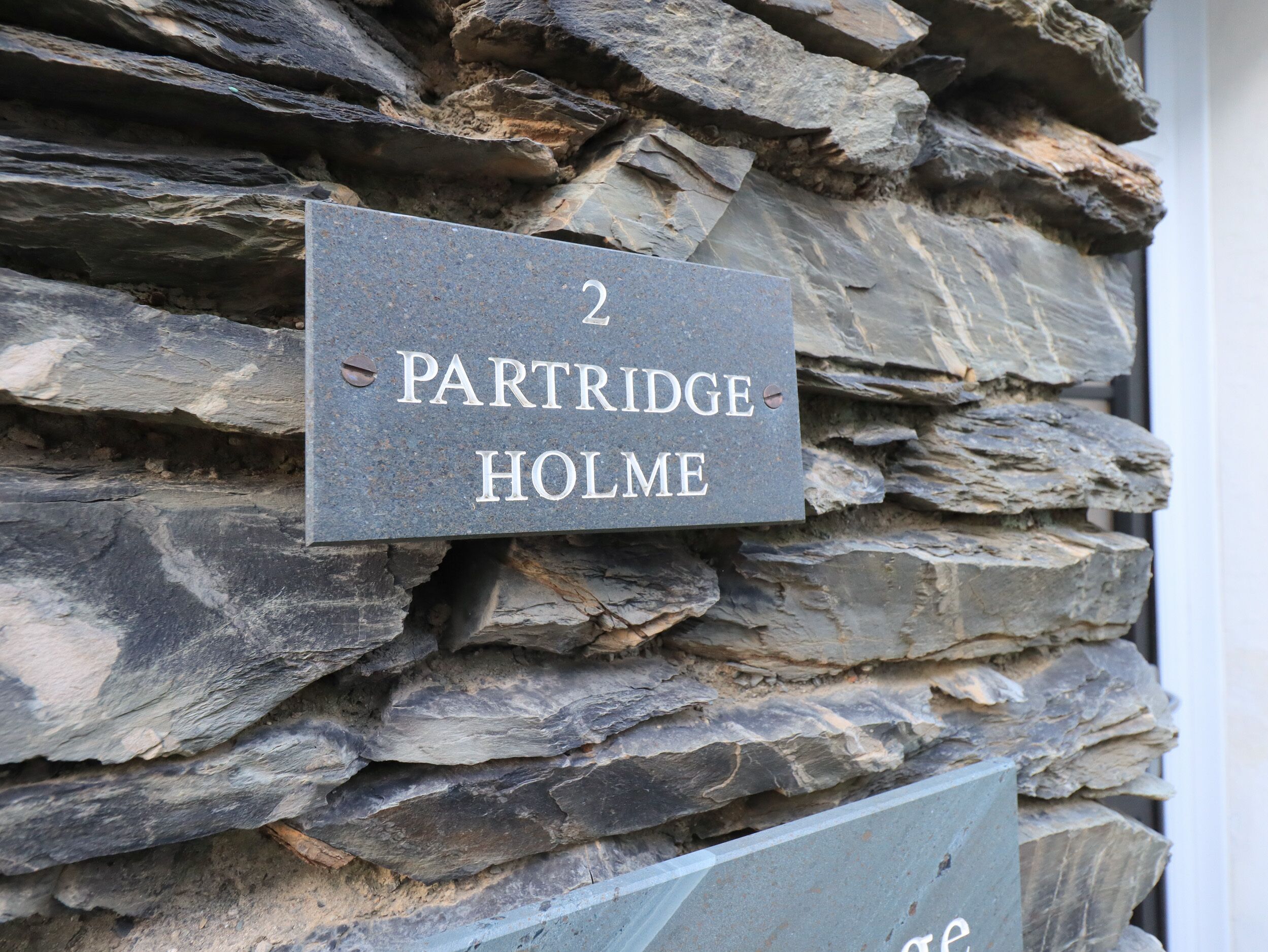 Un mur de pierres sur lequel est apposée une plaque indiquant « 2 PARTRIDGE HOLME ».