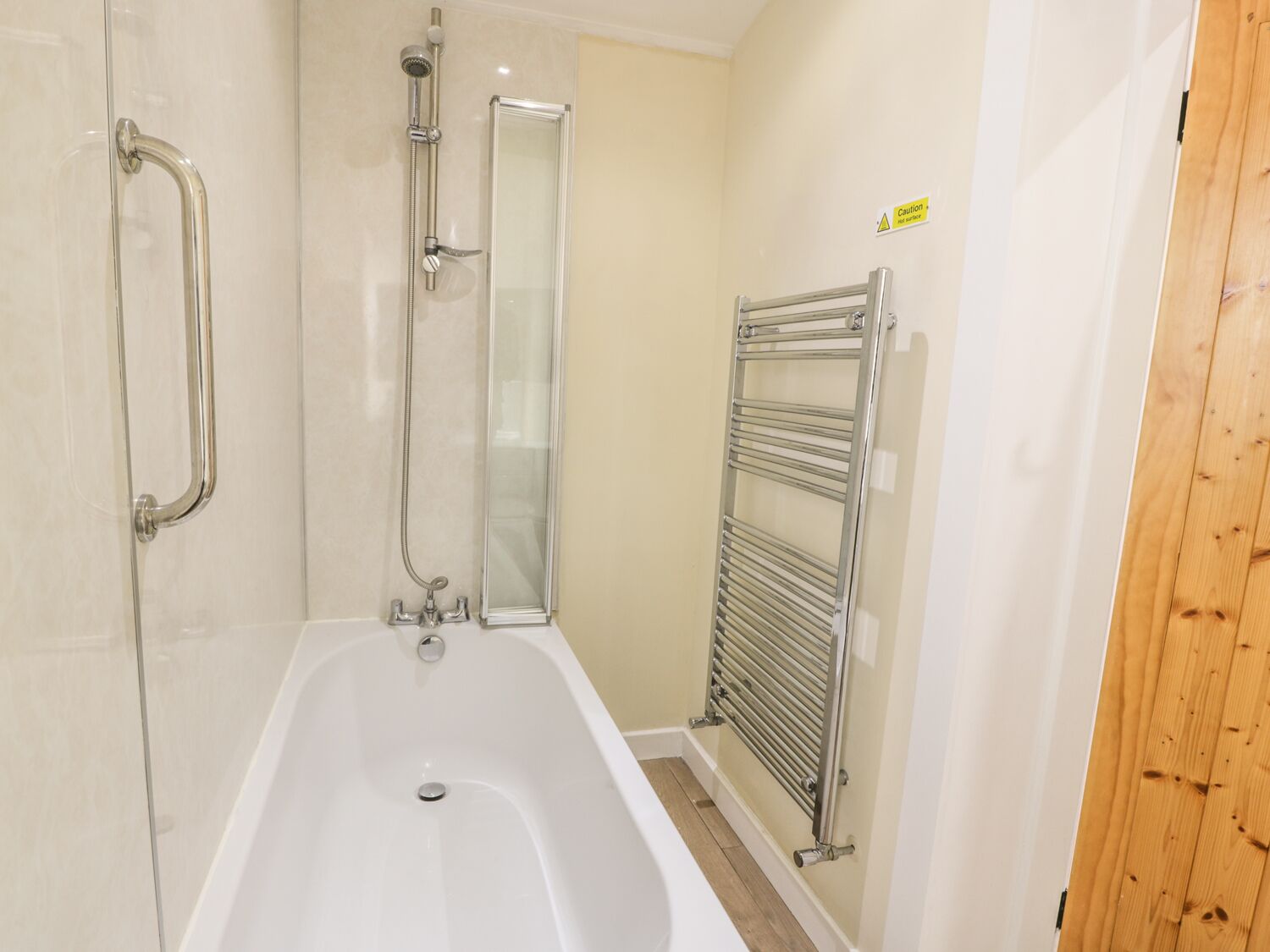 Ein Badezimmer mit Duschkabine aus Glas, einer weißen Badewanne und einem Metallhandtuchhalter.
