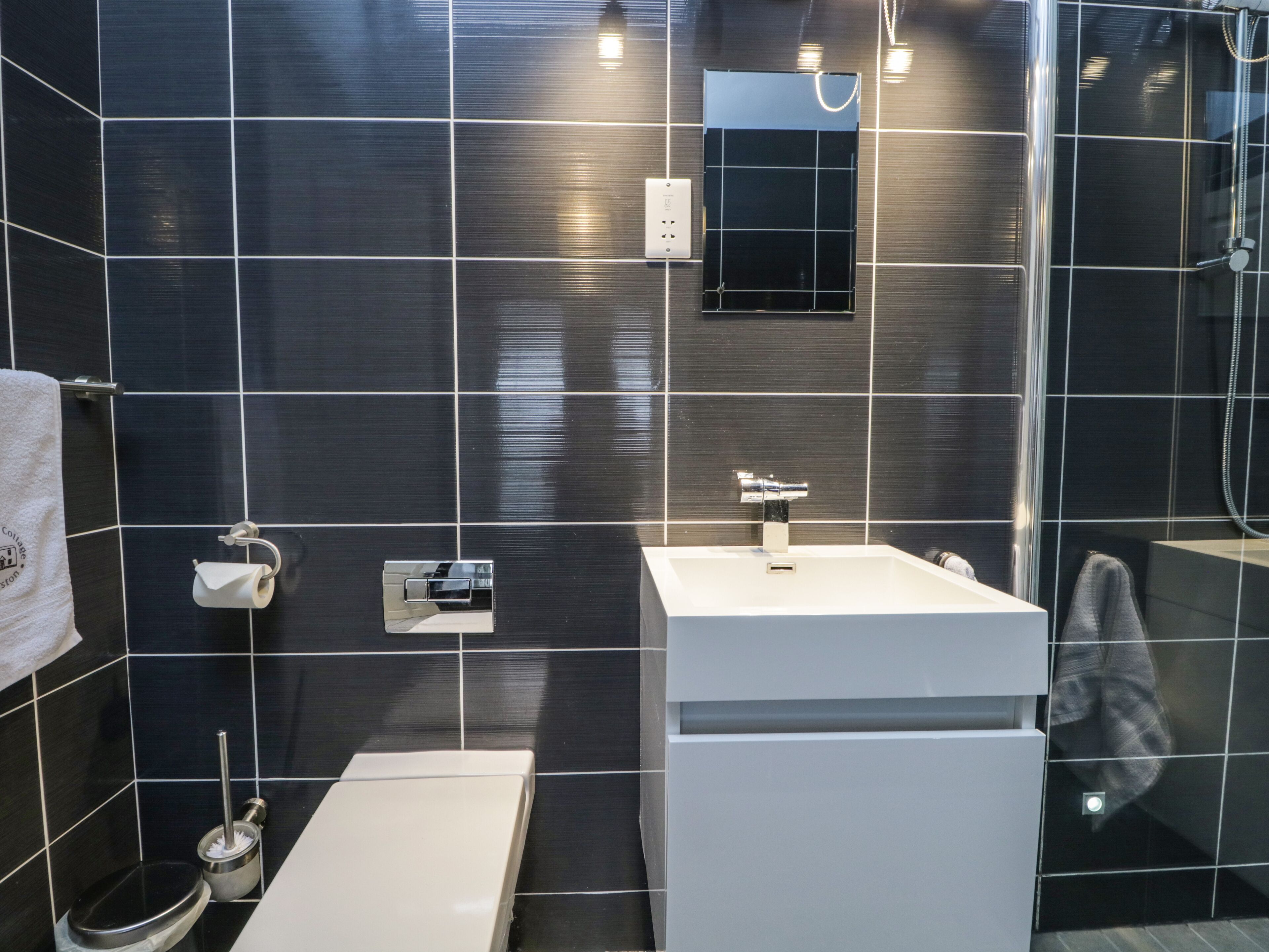 Ein modernes Badezimmer mit einem weißen Waschbecken, einer Toilette und einer Dusche.