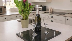 A kitchen with a potted plant, a bottle of wine, and two glasses on a black tray. - Heathylee (Buxton)