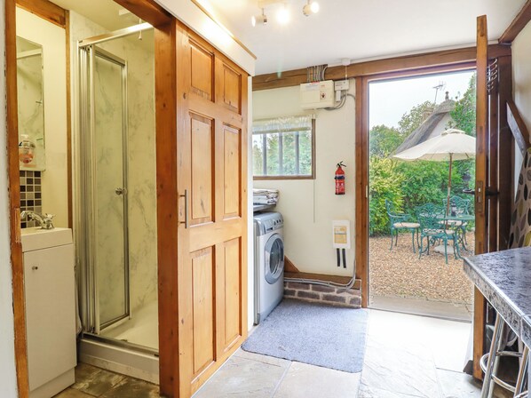 A kitchen with wooden cabinets, a washing machine, and a fire extinguisher. - The Studio, Horseshoe Cottage (Cambridge)