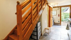 A wooden staircase with a handrail, leading to a room with a stone floor and a view of the outdoors. - The Studio, Horseshoe Cottage (Cambridge)