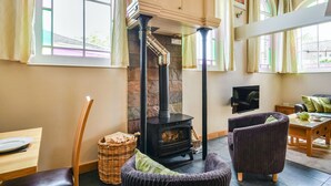 A cozy room with a stone fireplace, wicker furniture, and large windows. - The New Chapel (Hull)