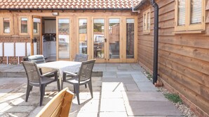 Un patio con una mesa y sillas, una cerca de madera y un techo de tejas.