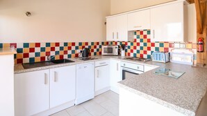 Una cocina con armarios blancos, un salpicadero colorido, un fregadero, un microondas, un tostador y un hervidor.