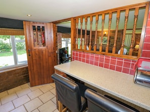 A kitchen with a wooden door, a tiled backsplash, and a bar area.