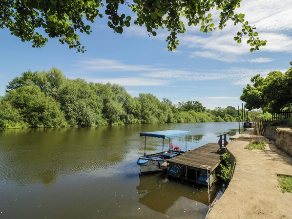 A riverside dock with boats, a covered area, and a concrete walkway. - Severn Bank Lodge (Bewdley)