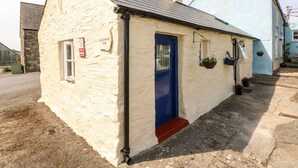 A small, single-story building with a blue door and a white window. - Ffynnon Tom (Haverfordwest)