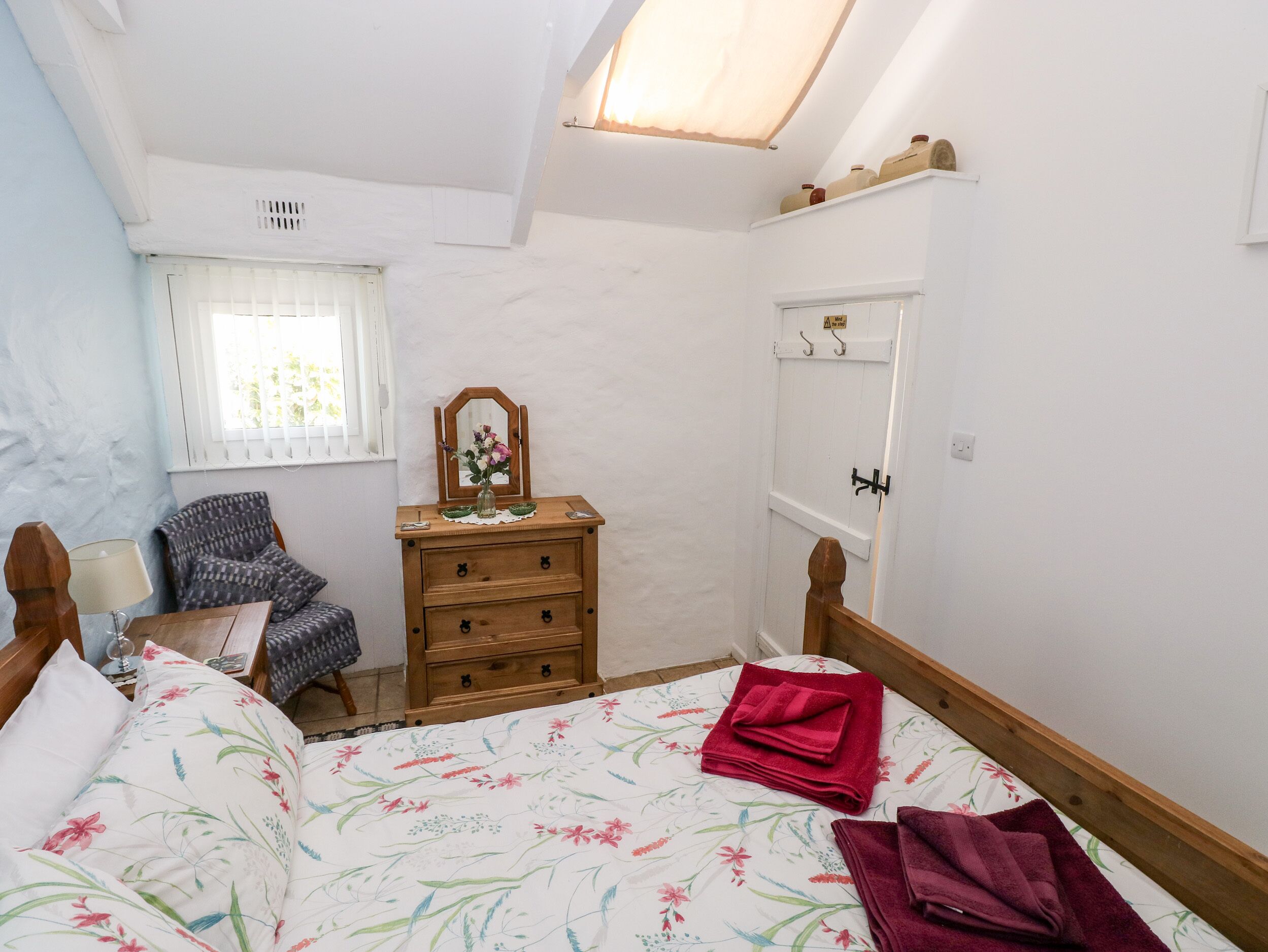A bedroom with a bed, a dresser, a chair, a window with blinds, and a ceiling fan.