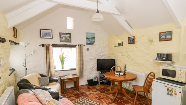 A cozy living room with a sofa, a dining table, and a TV. - Ffynnon Tom (Haverfordwest)