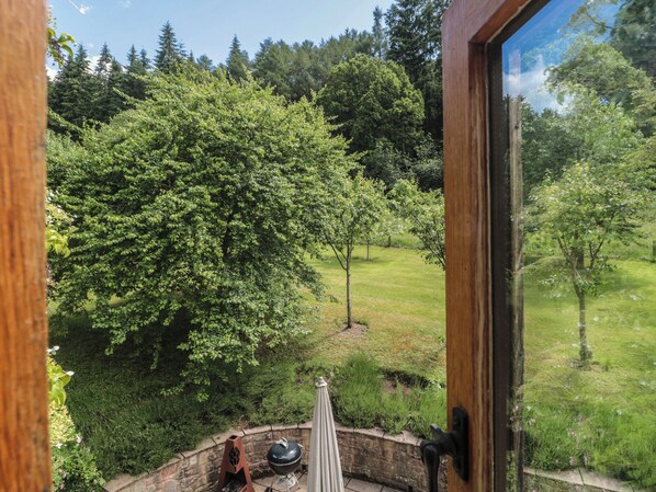 A view from inside a building with a large window overlooking a grassy area with trees. - The Lodge Farm Barn (Ross-on-Wye)