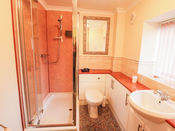 A bathroom with a glass-enclosed shower, a toilet, a sink, and a mirror.