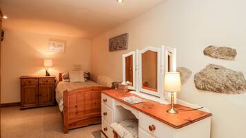 Un dormitorio con una cama de madera, un aparador de madera con cajones, un espejo y una lámpara.