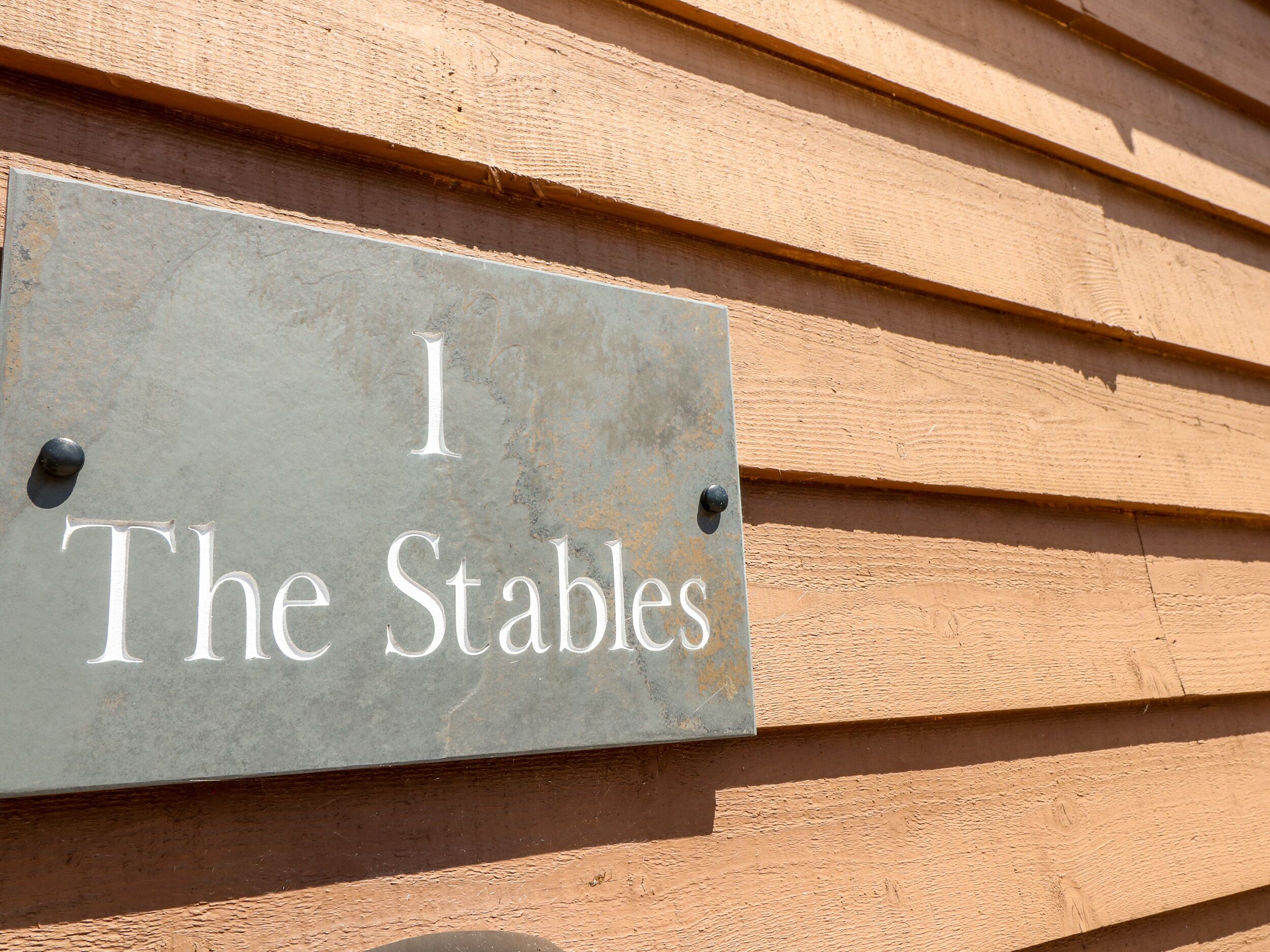 A sign on a wooden wall that reads "I The Stables".