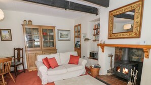 Un salon chaleureux avec un canapé blanc, des coussins rouges, une cheminée, des meubles en bois et un grand miroir.