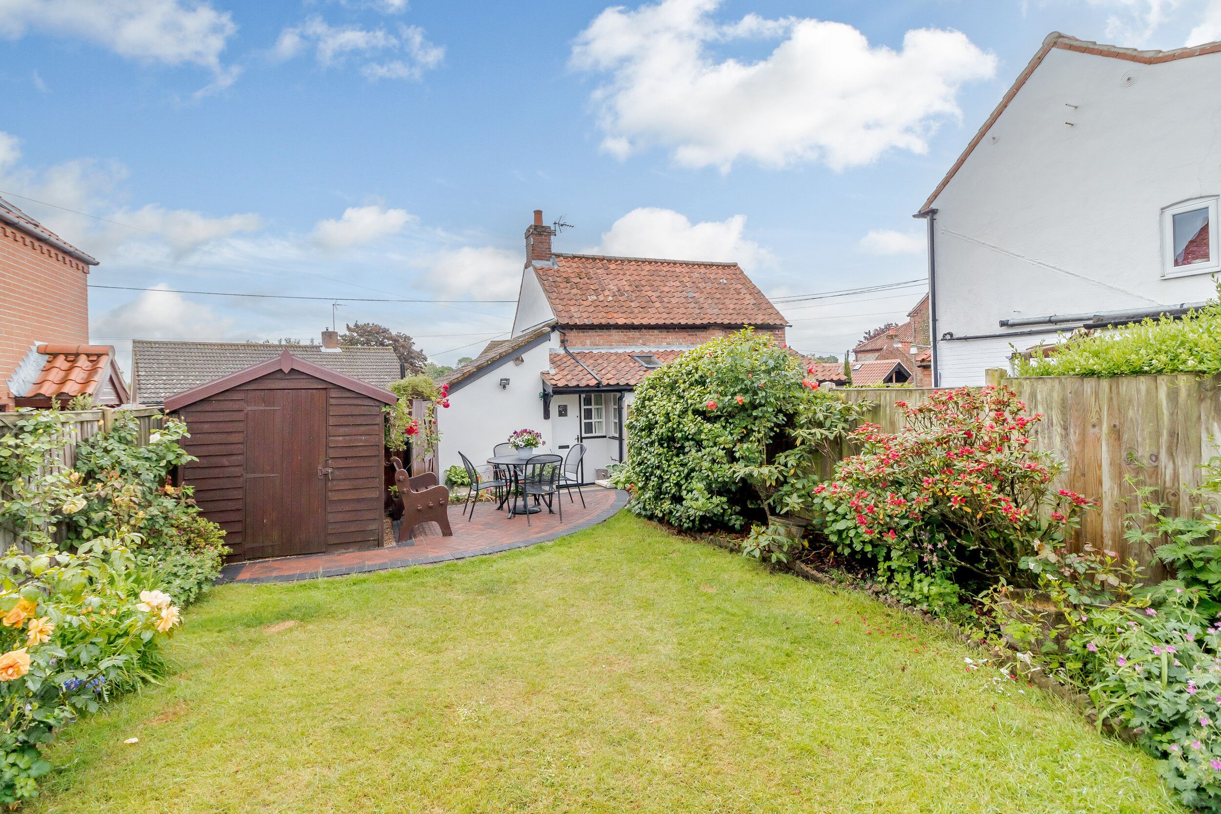A residential backyard with a patio, a shed, and a house with a tiled roof.