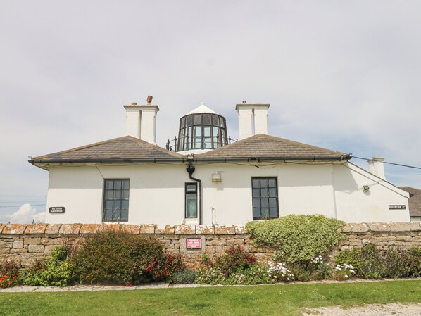 A white building with a cylindrical tower, a reception sign, and a private car park sign. - Old Higher Lighthouse Stopes Cottage (Portland)