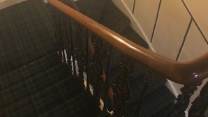 A staircase with a wooden handrail and black balusters.