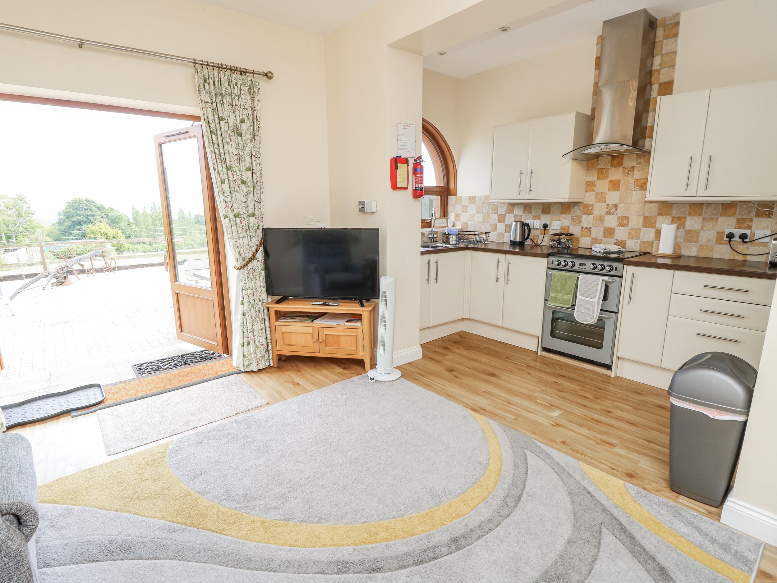 A compact kitchen with a built-in oven, a large window, and a television on a wooden stand.