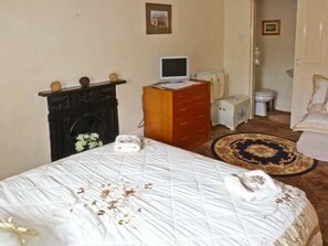 A neatly arranged bedroom with a bed, dresser, and a small desk with a computer.