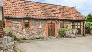 Ein Steinhaus mit Ziegeldach, einer Holztür und einem kleinen Fenster.