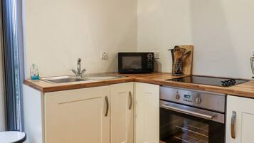 A compact kitchen with a sink, a microwave, a stove, and a built-in oven.