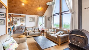 A cozy living room with a fireplace, large windows, and a wooden ceiling. - Thorsvik (Sleat)