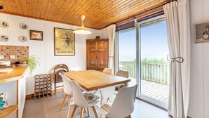 A wooden ceiling, a dining table with chairs, a kitchen area, and a balcony with a view. - Thorsvik (Sleat)