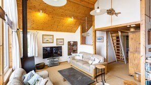 A cozy living room with a fireplace, sofa, TV, and wooden ceiling. - Thorsvik (Sleat)