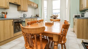 Una cocina moderna con armarios de madera, una mesa de comedor con sillas y vistas a la ciudad a través de amplios ventanales.