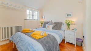 Une chambre à coucher avec un lit, une table de chevet, une fenêtre et un radiateur.