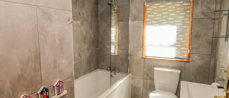 A modern bathroom with a bathtub, toilet, and a shower area.