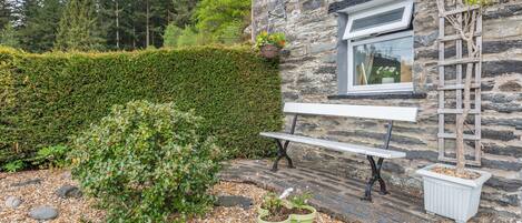 A stone building with a bench and potted plants in front.