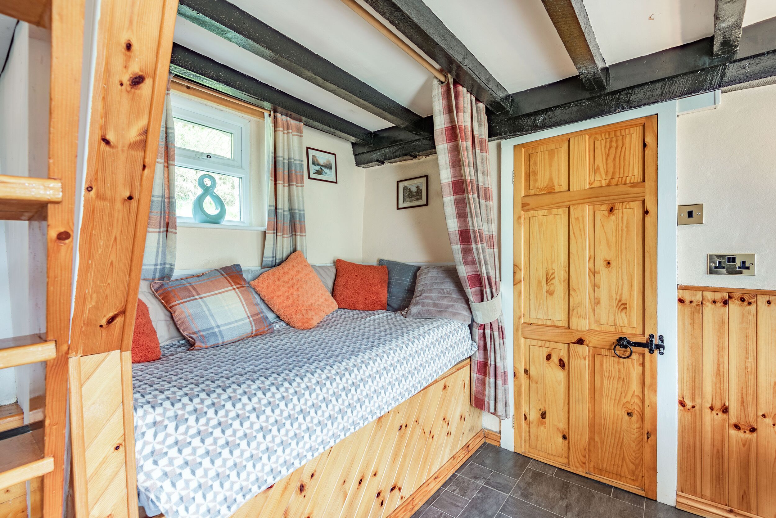 A cozy room with a wooden bed, a window with curtains, and a wooden door.