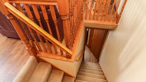 Eine Holztreppe mit Handlauf, Teppichstufen und einer Tür am unteren Ende.
