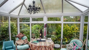 A conservatory with a table, chairs, and a chandelier. - Dorrington Court (Shrewsbury)