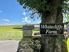 Escape to the serene countryside at Whitecliffe Farm, surrounded by open fields and a picturesque stone wall.