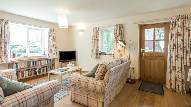 A cozy living room with a sofa, a coffee table, a bookshelf, and a television.