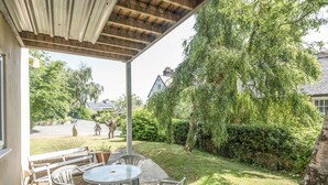 A covered patio with outdoor seating, a grassy area, and a view of a residential neighborhood.