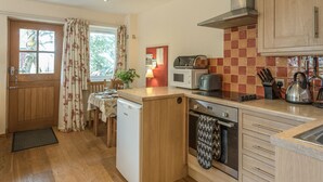 A compact kitchen with wooden cabinets, a microwave, a kettle, and a small oven.