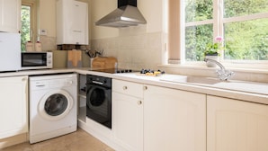 A modern kitchen with a built-in oven, microwave, washing machine, and dishwasher. - Hill Top Cottage (Lincoln)