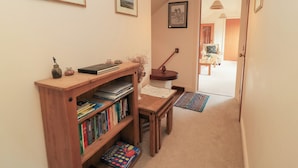 A hallway with a wooden bookshelf, a desk, and a chair. There are framed pictures on the walls and a hanging lamp. - Uplands (Sherborne)