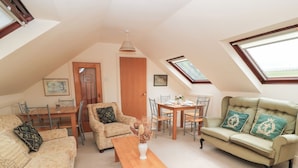 A cozy loft apartment with a dining area, a sofa, and a window with a view. - Uplands (Sherborne)