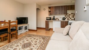 A compact living space with a dining area, a sofa, a kitchen with modern appliances, and a patterned rug. - Wisteria Chalet (Highbridge)